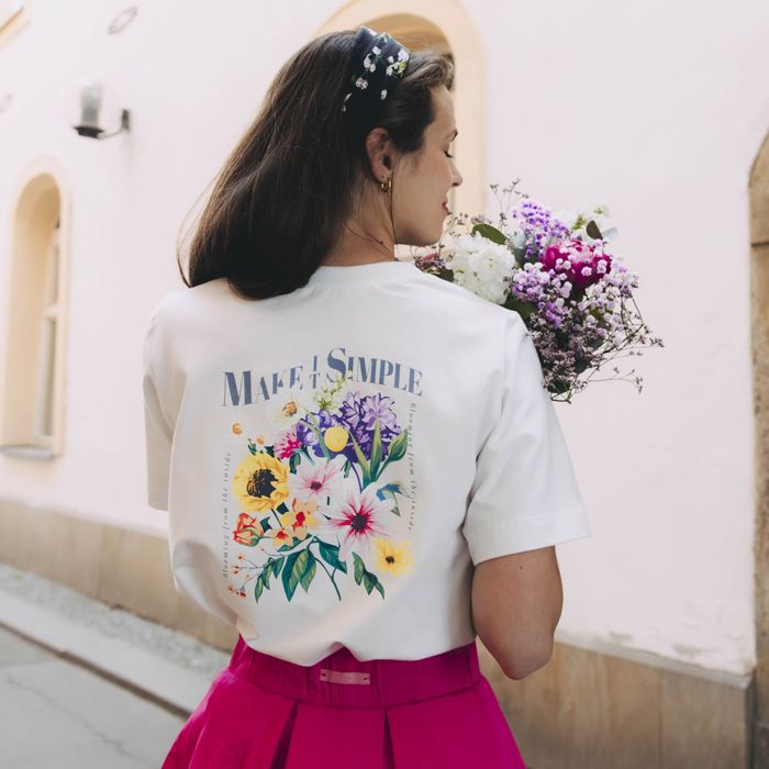 Kačka si užívá letního dne v bílém tričku Nia s květinovým potiskem na zádech. Tričko pochází z kolekce Mood od značky Buga.