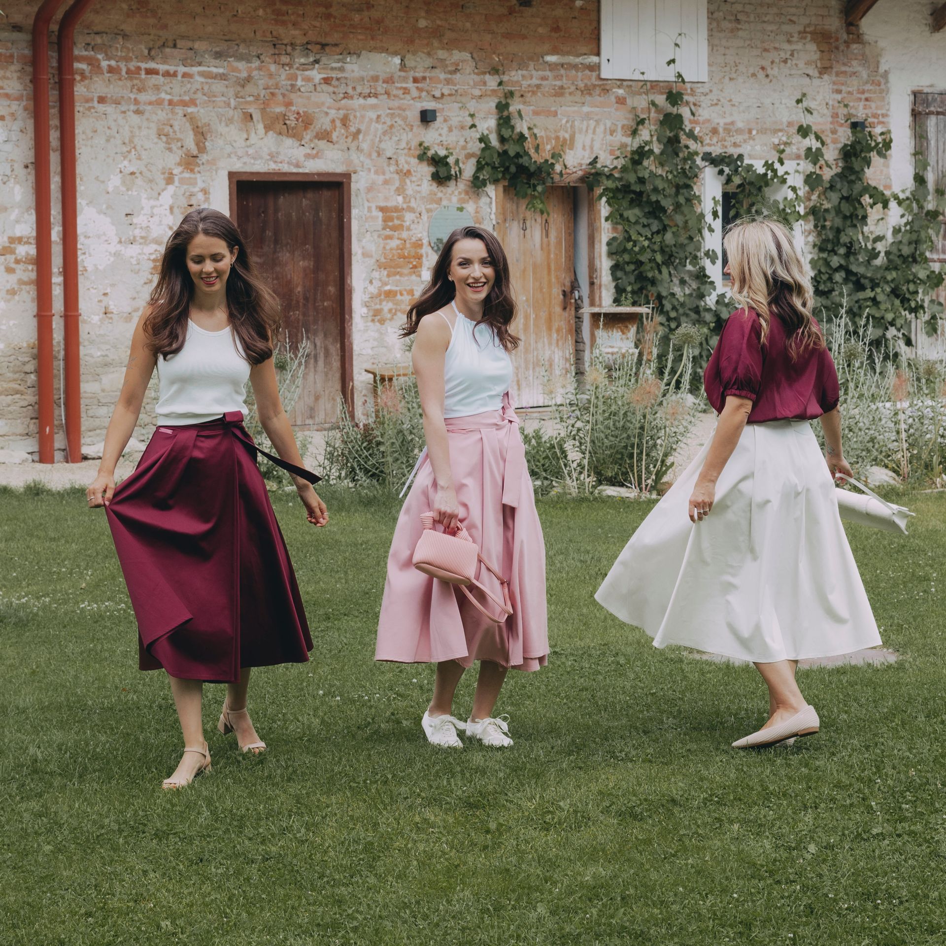 Holky mají na sobě zavinovací sukni Mawe ve třech barvách - bordó, světle růžová a béžová. Ušité v Čechách, promyšlené do každého detailu.