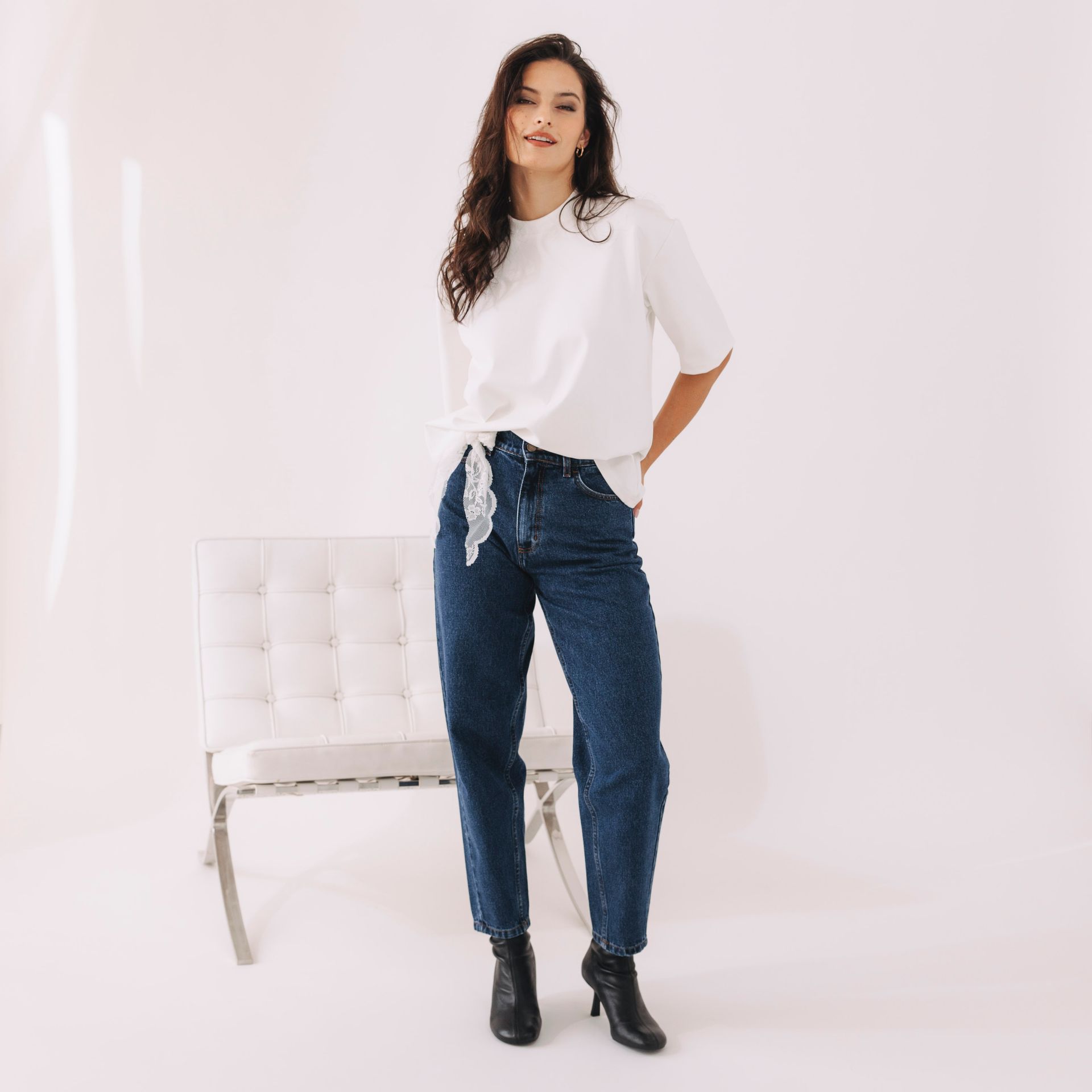 Anička si obliekla tmavé džínsy v strihu ikonických mrkváčov a biele basic tričko. Celý komplet doplnila opaskom z bielej čipky. Ušité v Česku, v duchu udržateľnej módy.