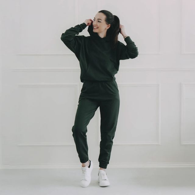 Tmavozelená mikina s kapucňou a tmavozelené tepláky vytvárajú skvelý monochromatický outfit. Je to tepláková súprava z českej dielne, ktorá je pohodlná, štýlová a trendy.