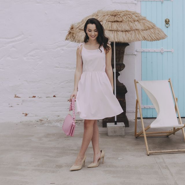 Káťa má na sobě světle růžové šaty Imani, které mají úzká ramínka a délku nad kolena. Ušité s láskou v české dílně Buga.